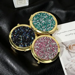 Close-up of sparkling rhinestone folding makeup mirrors in green, black, and pink.