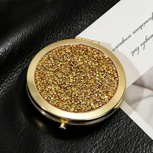 High-quality close-up of a gold round makeup mirror featuring sparkling glitter finish
