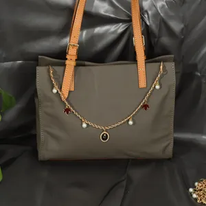 Détail d'une chaîne de sac dorée élégante avec perles et breloques à fleurs sur sac en cuir