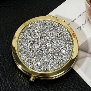 Detailed view of the sparkling rhinestone surface on a gold circular folding mirror