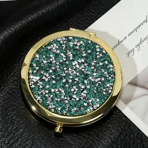 Detailed close-up of a portable round folding mirror with green glitter and silver studs