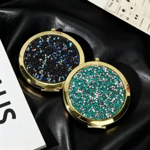 Detail of portable folding double-sided makeup mirrors with glitter and gold metal frame.