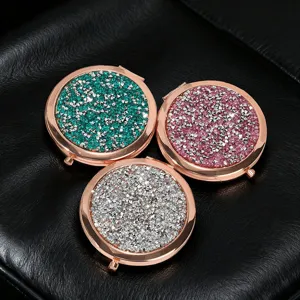 Close-up of three glittered metal folding mirrors in green, pink, and silver colors.