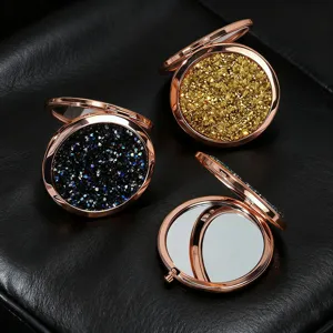 Close-up of rose gold compact mirrors with gold glitter and black gemstone textures
