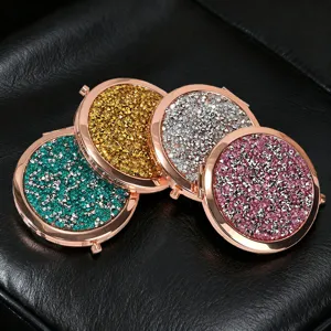 Close-up of four glittery circular compact mirrors in various colors on black leather.