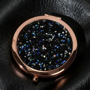 Detailed close-up of rose gold folding makeup mirror with sparkling black crystal inlay