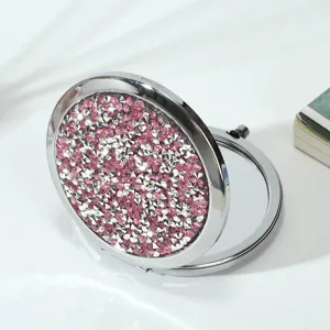 Detail view of sparkly pink rhinestone decoration on a round folding makeup mirror.