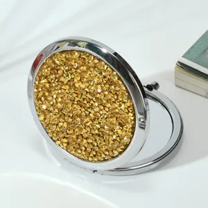Close-up of golden rhinestone lid on a round folding metal makeup mirror