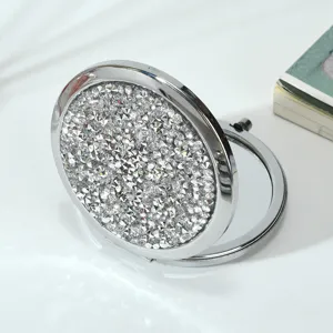Close-up of sparkling rhinestone-covered foldable metal compact makeup mirror