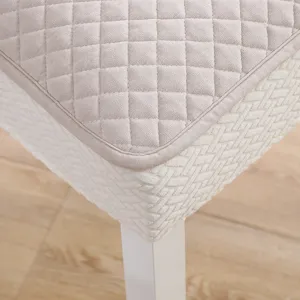 Détail de housse de chaise de salle à manger matelassée avec tissu beige et belles coutures.