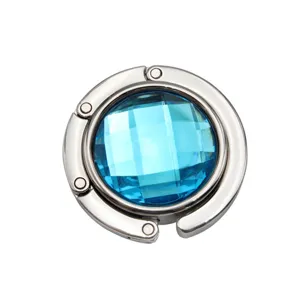 Detailed view of a foldable circular metal purse hook with a faceted blue gemstone.