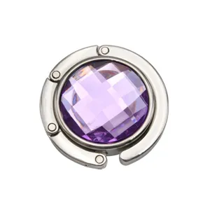 Detailed view of portable folding metal bag hook with a purple faceted gemstone.