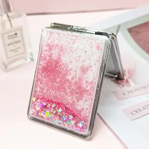 Close-up detail of a portable pink quicksand folding makeup mirror with glitter.