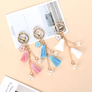 A group of cute tassel keyrings with cherry blossom charms and pearls on a beige background