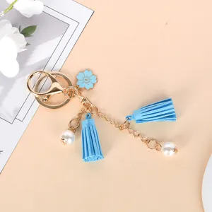 Detail of cute light blue keychain with flower charm, tassels, and faux pearls.