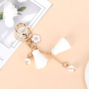 Close-up of elegant gold keychain with white cherry blossom, tassels and pearls