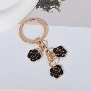 Detailed view of a boutique gold-plated keychain with three black enamel rose charms.