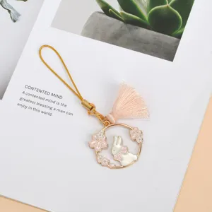 Detail view of a cute enamel rabbit charm with pink cherry blossoms and a tassel.