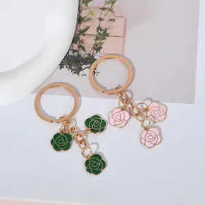 Close-up detail of green and pink rose charms on elegant gold-tone metal keychains