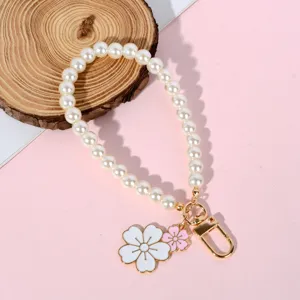Detailed view of pearl phone strap with white and pink enamel flower charms and gold clasp