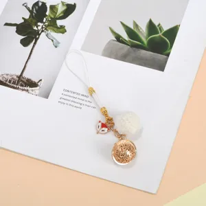 Detailed shot of cute fox phone strap with gold filigree bell and white pom-pom charm