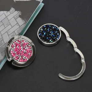 Detailweergave van opvouwbare tassenhaken met fonkelende roze en zwarte strass