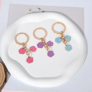 Detailed view of three enamel rose keychains in pink, purple and blue with gold rings