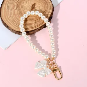 Close-up view of a pearl bead strap with an elegant pearl bow charm and gold clasp