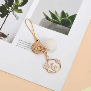 Detail of cute gold bunny charm with white pom-pom and cherry blossom design