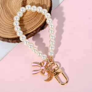 Elegant faux pearl phone lanyard featuring a pink enamel bow and crescent moon charm