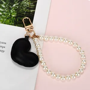 Detailweergave van witte parelketting met een zwarte hartvormige hanger van kunstleer