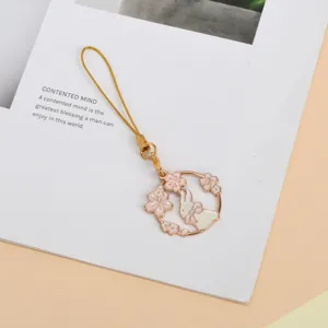 Macro detail view of a cute enamel rabbit and pink cherry blossom charm phone strap.