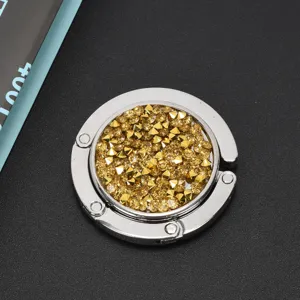 Macro-opname van een opvouwbare tassenhaak met fonkelende gouden strass-steentjes.