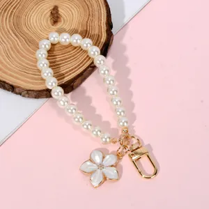 Detailed view of white pearl phone strap with elegant white flower charm and gold clasp