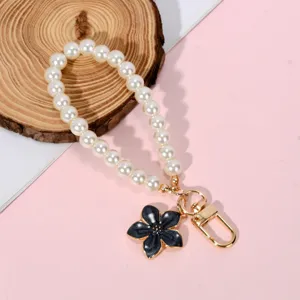 Elegant pearl chain phone strap featuring a black flower charm and gold lobster clasp.