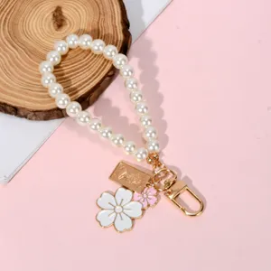 Elegant pearl bead keychain with white flower and gold portrait charms