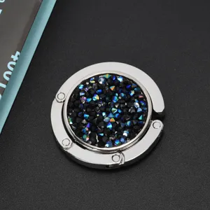 Gedetailleerde close-up van een opvouwbare tassenhaak met fonkelende donkere strass-steentjes