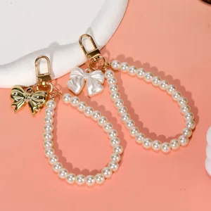 Macro view of elegant pearl phone charms with golden and pearlescent bow details