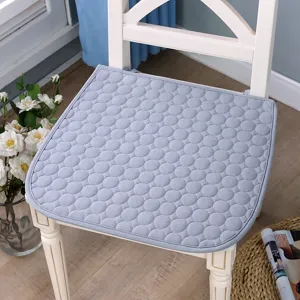 Vue détaillée d'un coussin de chaise gris clair matelassé à motifs circulaires sur chaise en bois.