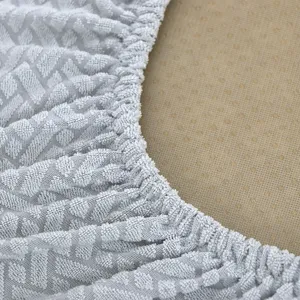 Gros plan de la texture du housse de chaise extensible grise, détail du bord élastique.