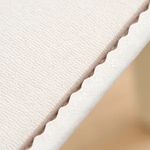 Detailopname van zacht gewatteerde kussentoftextuur, nette stiksels en geschulpte rand.