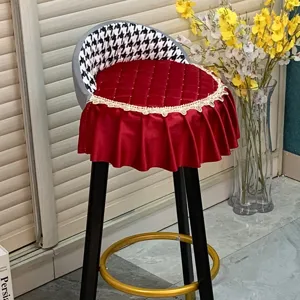 Gros plan sur la housse de tabouret matelassée rouge avec dentelle et dos en pied-de-poule.