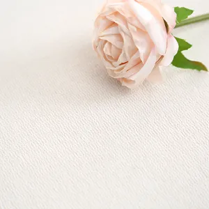 Detailopname van gestructureerde gewatteerde kussenstof met roze kunstmatige roos.