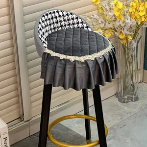 Détail de housse de tabouret de bar en velours, motif pied-de-poule et bordure en dentelle élégante.