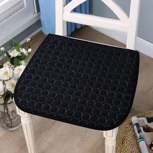 Vue détaillée du coussin de chaise matelassé noir à motif de points géométriques, assise confortable.