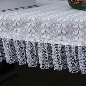 Vue détaillée de la housse de piano en dentelle blanche avec motif de feuilles et bordure plissée.