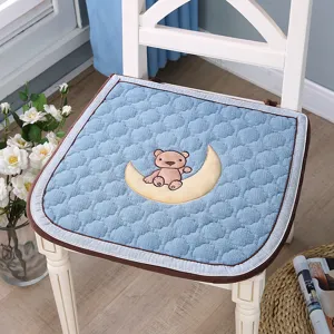 Vue détaillée du coussin de chaise bleu matelassé avec une jolie broderie d'ours et de lune.