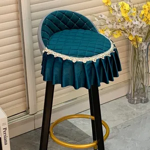 Housse de tabouret de bar en velours vert foncé avec dossier incurvé et bordure en dentelle.