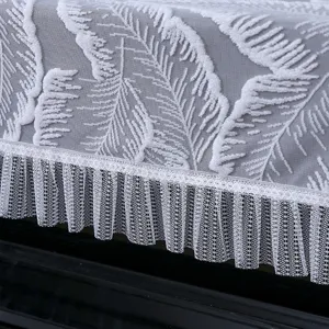 Detail de la belle housse de piano en dentelle blanche avec motif plumes et bord plisse.