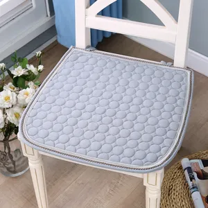 Vue détaillée du coussin de chaise matelassé gris clair avec motif à pois et bordure soignée.